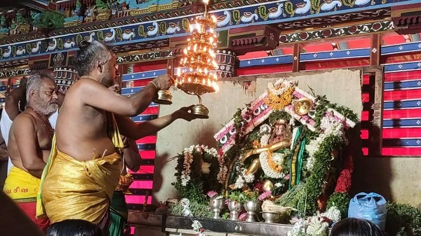 Priests performing deepa aradhanai to Kuttralanathar who is bedecked with flower garlands in Piravipini Theerkum Thirukutralam Temple