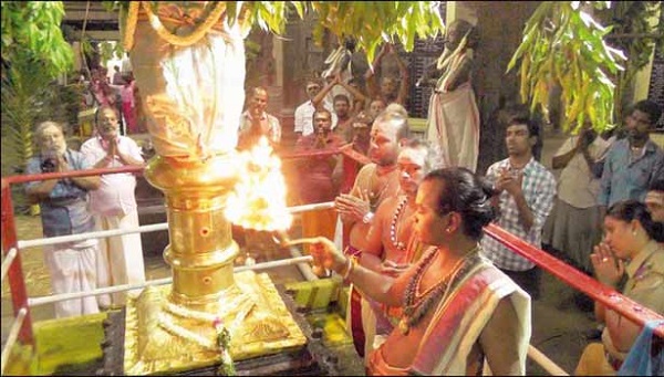 Priests commemorate the Chithirai Vishu festival with the hoisting of the holy flag. The flagmast is decorated with a garland and adorned with sandalwood and kumkum in Thirukutralam Temple 