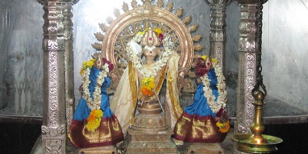 The presiding deity Lord Murugan with his consorts Valli and Deivanai in Thirumalai Kumaraswamy temple in Panpozhi. He is standing on a bronze pedestal inside a pillared structure holding the Vel and Flag. 