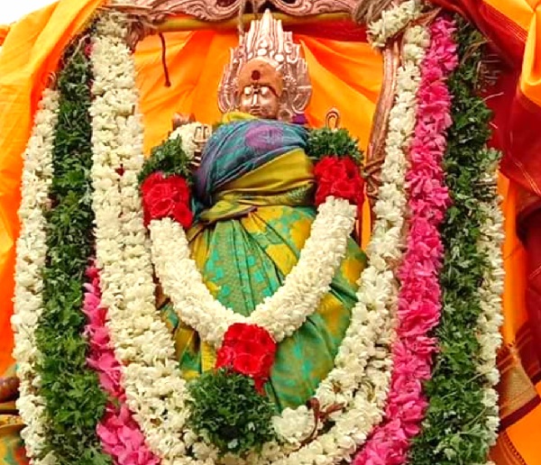 The presiding deity Pittapurathi temple Amman in Tirunelveli dressed in green and blue attire, wearing sandalwood paste and kungumam on her forehead and decked in several garlands.
