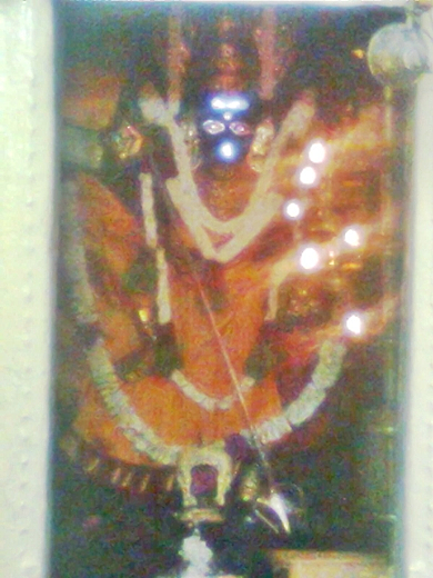 Sri Pittapurathi Amman dressed in an orange colour silk attire and decked with several garlands, and holding the trident. 