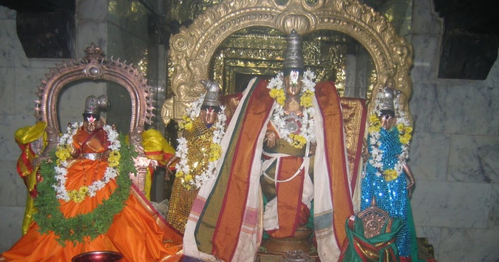 Utsava idols of Srinivasa Perumal of Thiruvenkatanathapuram Perumal temple with goddesses Sreedevi and Bhoodevi dressed in silk and floral garlands.