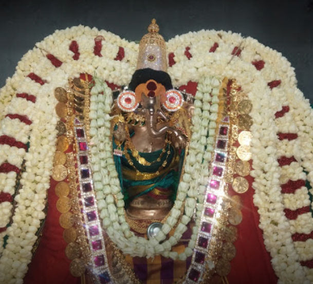 golden statue of lord ganesh decorated with flowers and jewels.