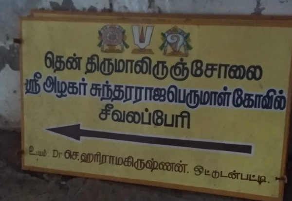 A yellow name board pointing direction to Sivalaperi Sundarraja Perumal temple in Tirunelveli placed against a wall