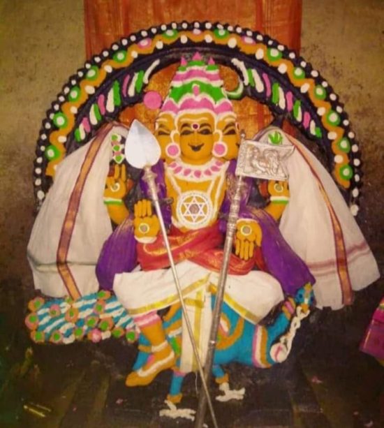 Idol of Palayansalai Kumaraswami smeared with sandalwood paste is visible sitting atop his peacock with a vel and a rooster flag placed to the left and right side respectively.