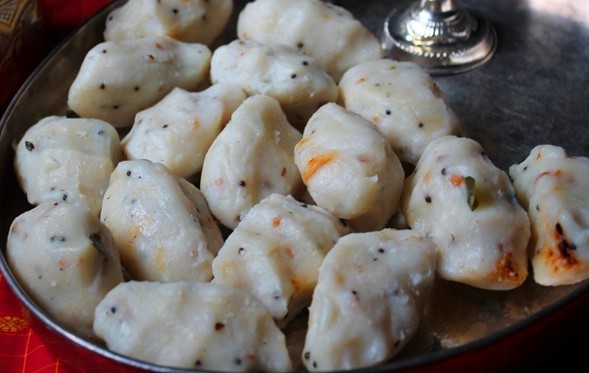 White nuggets of delicious spicy Pidi Kozhukkatai served on a stainless steel plate.