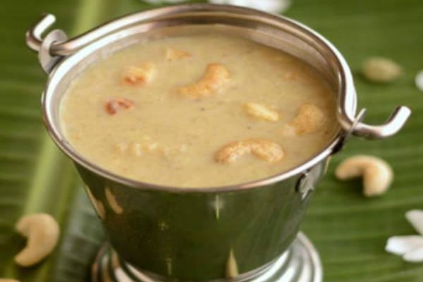 Delicious arisi payasam with golden brown ghee-roasted cashews served in a small stainless steel bucket placed on top of a banana leaf.