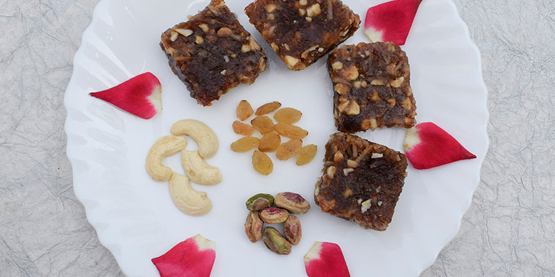 Rose halwa presented in a white plate with raisins, cashews and pistas.