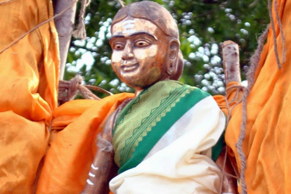 A copper statue of avaiyaar adorned with a silk saree in an attractive combination of ivory and green.