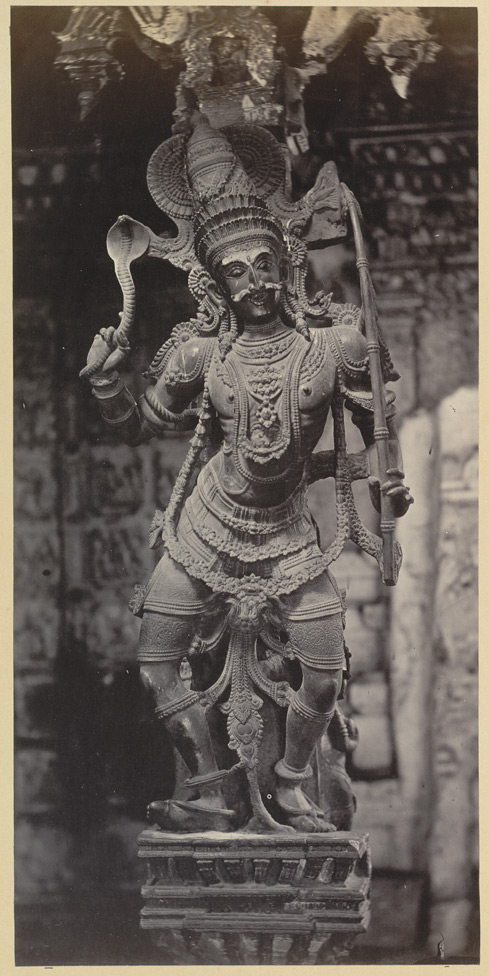 Statue of a Hindu god with a serpent on one hand and a bow and arrow on the other.