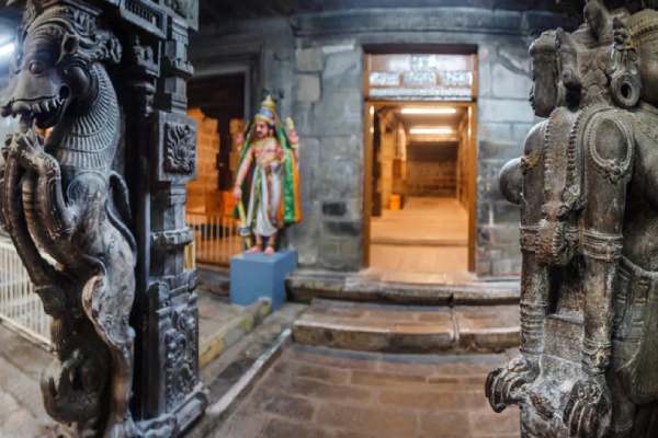 The front view of the nellaiyappar temple portrays stone statues carved on two stone pillars with an empty hallway at the back.